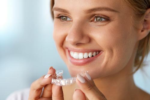 woman holding clear plastic aligner | cosmetic dentist cookeville tn