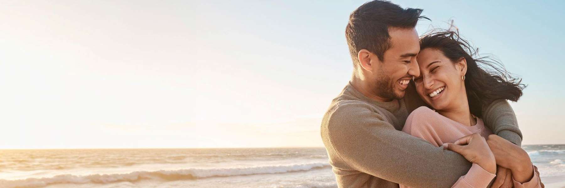 younger couple hugging on beach | dentist cookevill tn